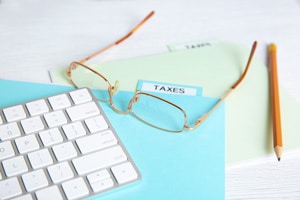 Tax files with glasses, pencil and keyboard on top