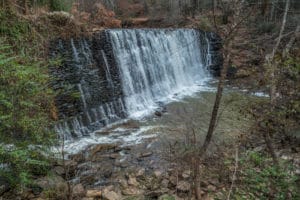 A close up view looking down from the trail at the waterfall at the old mill park in Roswell Georgia in winter